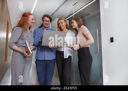 Aufnahmen aus der unteren Perspektive von Geschäftsleuten, die unterwegs einen Laptop benutzen und im Flur spazieren gehen Stockfoto