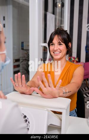 Junge Kundin lächelt fröhlich, während sie mit professionellen zufrieden ist Pflege im modernen Maniküre Salon Stockfoto