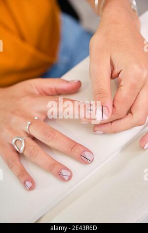Crop anonyme weibliche Klientin halten Handflächen auf Handauflage stehen Während der Maniküre Verfahren im professionellen Salon Stockfoto