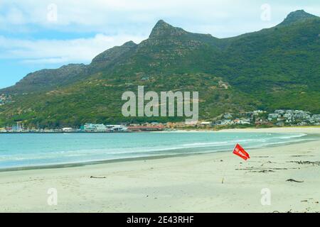 Hout Bay- Kapstadt, Südafrika - 19-01-2021 leuchtend rote 'No Swimming' Flagge weht im Wind am Hout Bay Strand. Stockfoto