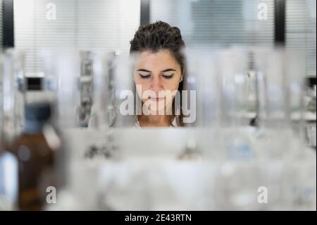 Konzentrierte junge professionelle Wissenschaftlerin, die am Tisch mit Glas arbeitet Kolben während der Forschung im medizinischen Labor Stockfoto