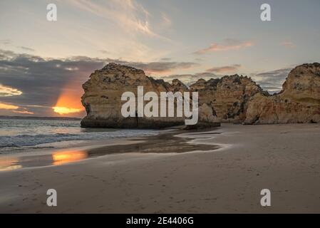 Spektakuläre Landschaft von rauen felsigen Klippen auf Praia da Rocha Sandstrand, der sich am Meer vor dem malerischen Sonnenuntergang wäscht In Algarve Stockfoto