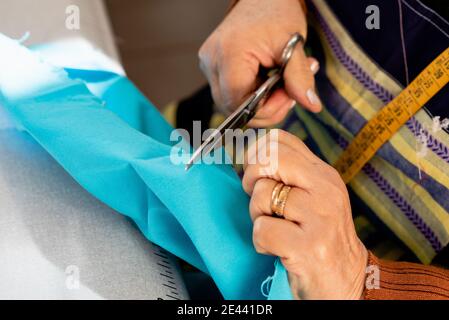 Hoher Winkel der Ernte anonyme ältere Schneiderin Schneidestück Stoff während der Arbeit in der Werkstatt Stockfoto