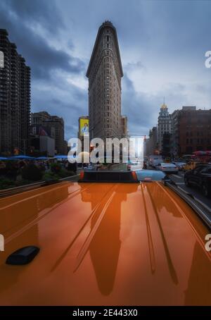 NEW YORK, EEUU - 21. September 2018 - niedriger Winkel des berühmten hohen dreieckigen Flatiron-Gebäudes spiegelt sich in dem Dach des Autos wider, das auf der Straße von manhattan geparkt ist Stockfoto