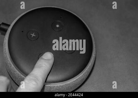LONDON/ENGLAND- 19. Januar 2020: Frau drückt einen Knopf auf einem Amazon Echo Dot Smart Speaker Stockfoto