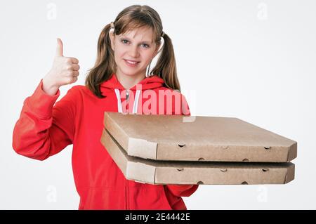 Junge lächelnde Frau in roter Uniform liefert Pizza in Schachteln - isoliert auf weißem Hintergrund Stockfoto