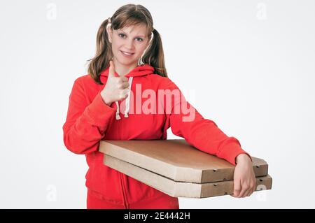 Junge lächelnde Frau in roter Uniform liefert Pizza in Schachteln - isoliert auf weißem Hintergrund Stockfoto