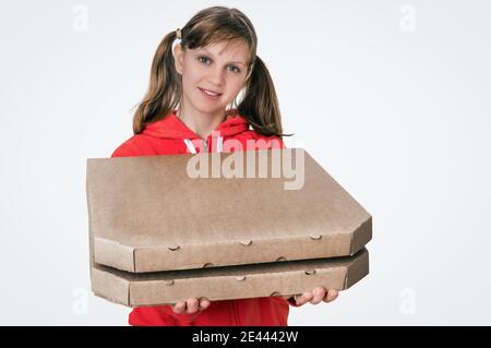 Junge lächelnde Frau in roter Uniform liefert Pizza in Schachteln - isoliert auf weißem Hintergrund Stockfoto