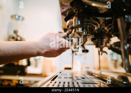 Anonyme Ernte männlichen Barista mit Portafilter Zubereitung Getränk in zeitgenössischen Kaffeemaschine während der Arbeit im Café Stockfoto