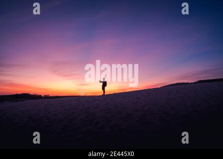 Silhouette von anonymen Touristen stehen auf sandigen Ufer und nehmen Bild von spektakulärem Sonnenuntergang in Cadiz Stockfoto