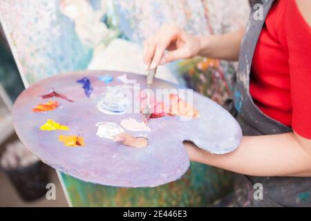 Nahaufnahme einer Palette, wo weibliche Künstlerin Ölfarbe mischen. Nicht erkennbare Frau, die im Kunststudio arbeitet Stockfoto
