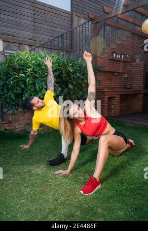 Fokussierter, fit-Sportler und Sportlerin, die in Utthita Parivrtta Anjaneyasana Yoga praktiziert, während sie sich beim Training in der Höflichkeit aufwärmt und den Körper dehnt Stockfoto