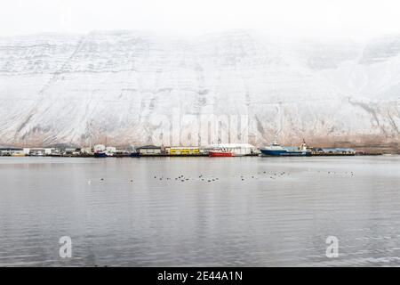 Landschaftlich schöne Aussicht auf Boote, die in der Nähe des Piers im Meer festgemacht sind Hintergrund von verschneiten Bergen im Winter in Island Stockfoto