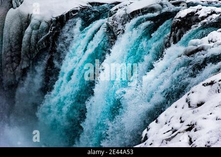 Majestätischer Blick auf den schnellen Wasserfall, der den felsigen Berg hinunterfließt Winter in Island Stockfoto