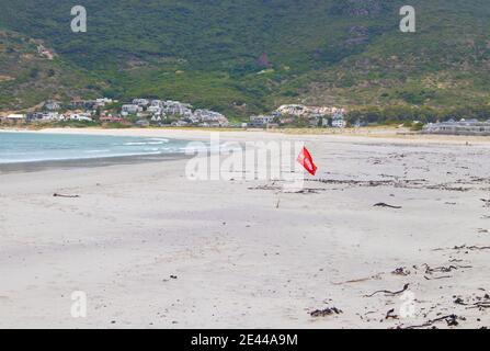 Hout Bay- Kapstadt, Südafrika - 19-01-2021 leuchtend rote 'No Swimming' Flagge weht im Wind am Hout Bay Strand. Stockfoto