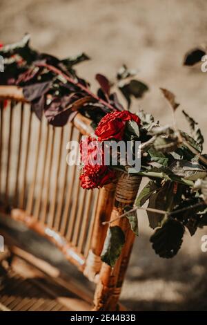 Hoher Winkel von Vintage Korbstuhl mit getrockneten Rose verziert Blumen und im Garten an sonnigen Tag für die Hochzeit platziert Feiern Stockfoto