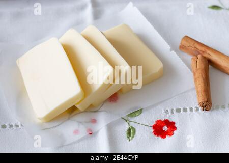 Von oben Scheiben Butter und aromatische Zimtstangen für Gebäck Vorbereitung auf Baumwolle Tischdecke auf Tisch zu Hause platziert Stockfoto