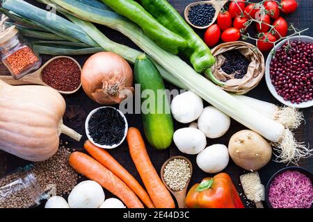 Von oben Layout von Bio-Gemüse im Sortiment und Getreide In Schüsseln und Gläsern auf Holztisch Stockfoto