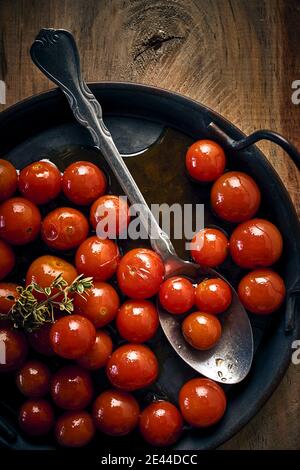 Draufsicht auf hausgemachte marinierte Kirschtomaten und Löffel platziert Auf Pfanne auf Holztisch in rustikaler Küche Stockfoto