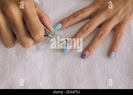 Von oben der Ernte nicht erkennbare junge weibliche Schneide Nagelhaut mit nipper im Schönheitssalon Stockfoto
