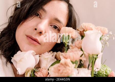 Nahaufnahme Porträt der jungen Frau mit Blumenstrauß und natürlichen Look. Nahaufnahme im Frühling. Ernst und romantischen Ausdruck mit weit geöffneten Augen Stockfoto