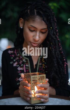Junge afro latina Frau, die eine Kerze in den Händen hält Stockfoto