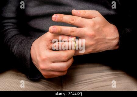 Enttäuschter Mann nimmt seinen Ehering isoliert auf Schwarz - Scheidung Konzept Stockfoto