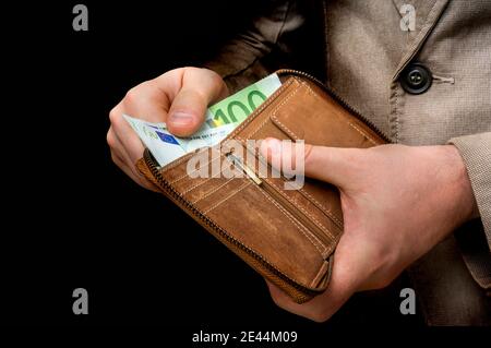 Braune Lederbörse mit Euro-Geld in männlichen Händen isoliert Auf Schwarz Stockfoto