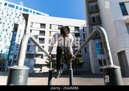 Männlicher Unternehmer in edlem Anzug Balancing in Handstand auf Metall Geländer in der Stadt, während vorformende Parkour Trick Stockfoto