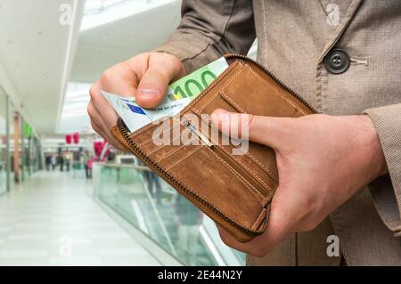 Braune Lederbörse mit Euro-Geld in männlichen Händen Einkaufszentrum Stockfoto