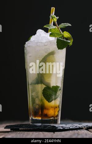 Glas mit kaltem Alkohol Mojito Cocktail mit Rum und frisch Limette serviert mit Eis und Minzblättern auf Holztisch Stockfoto