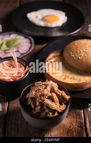 High-Winkel-Set von Zutaten für gezogen Schweinefleisch Hamburger mit Gemüse und Spiegelei auf Holztisch angeordnet Stockfoto
