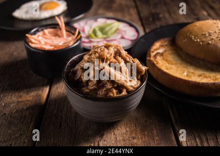 High-Winkel-Set von Zutaten für gezogen Schweinefleisch Hamburger mit Gemüse und Spiegelei auf Holztisch angeordnet Stockfoto