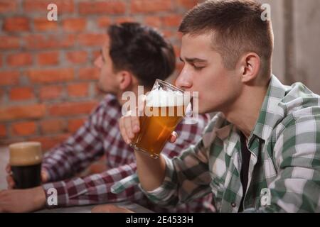 Junger Mann schlürft leckeres Bier im Pub Stockfoto