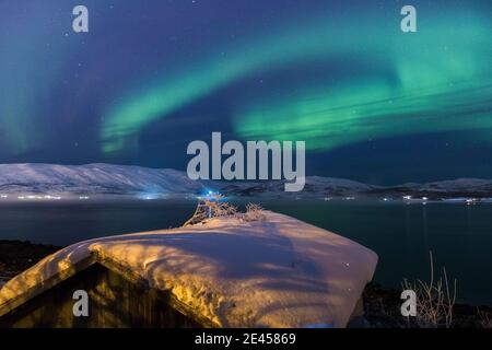 Nordlichter über einem schneebedeckten Dach. Stockfoto