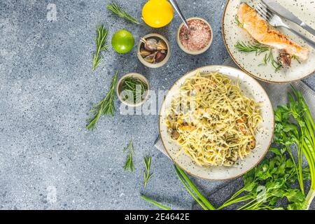 Pasta Linguine mit Pilzen, Garnelen und Meeresfrüchten Muscheln, Käse und Kräutern, in Keramikplatte auf einer hellgrauen Oberfläche. Stockfoto