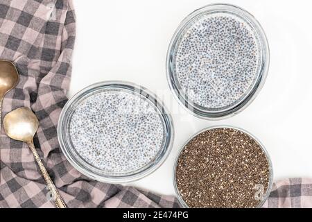 Chia Samen in einer Glasschüssel und Chia Samenpudding auf weißem Hintergrund, flach legen Stockfoto