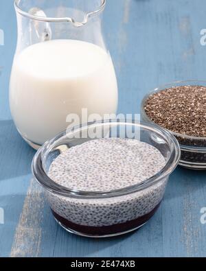 Chia Samen, Milch und Chia Samenpudding Nahaufnahme auf blauem Holzhintergrund, vertikales Banner Stockfoto