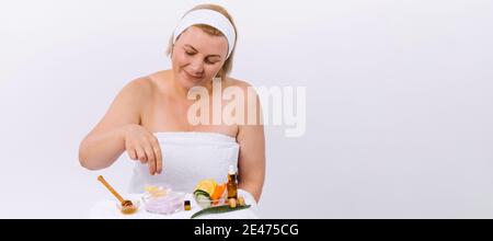 Banner. Eine ältere Frau zu Hause, in einem weißen Handtuch verpackt bereitet eine Gesicht und Körpermaske aus natürlichen Produkten. Hausgemachte Hautpflege und Hautpflege Stockfoto