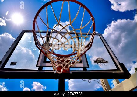 Blick nach oben Blick auf ein Basketball-Netz und Hintergrund Gegen den blauen Himmel mit einem Sonnenstern Stockfoto