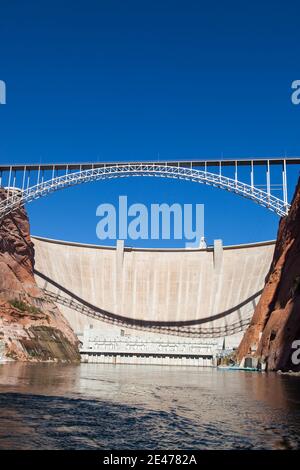 Der Glen Canyon Dam hält Lake Powell und die zurück Glen Canyon Brücke mit einem klaren blauen Himmel Hintergrund Von der Oberfläche des Colorado Rive aus gesehen Stockfoto