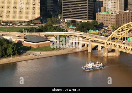 Ein Boot fährt am Fort Pitt Museum und der Bridge auf dem Monongahela River am Point State Park in der Innenstadt von Pittsburgh, Pennsylvania, USA vorbei. Stockfoto