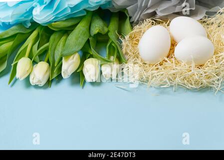 Osterhintergrund mit Eiern im Nest und weißen Tulpen. Stockfoto