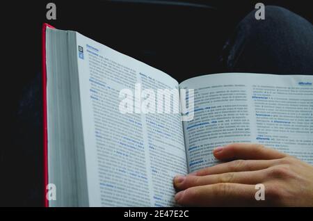 VALENCIA, SPANIEN - 10. Jan 2021: Bild der Hand hält ein offenes Wörterbuch zum Lesen. Stockfoto