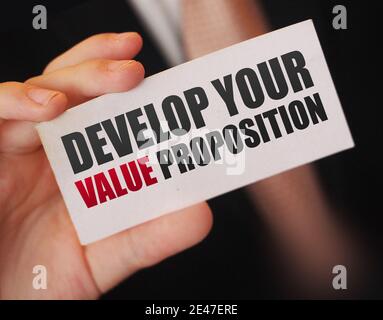 Geschäftsmann zeigt eine Karte mit Text ENTWICKELN SIE IHR WERTVERSPRECHEN. Management Business Achievements Motivationskonzept. Stockfoto