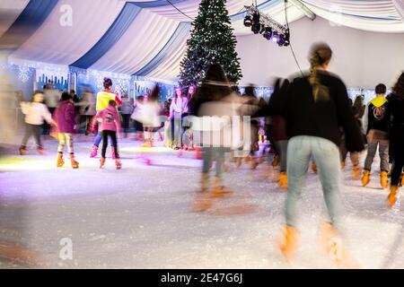 Malaga, Spanien - 08. Dezember 2017. Viele Menschen Schlittschuh auf große Eisbahn in der Winternacht, Bewegungsunschärfe Stockfoto