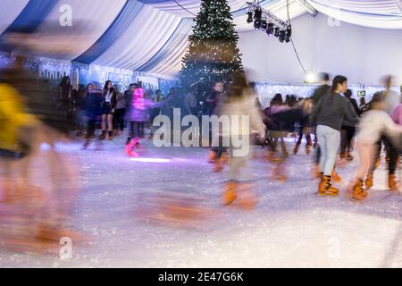 Malaga, Spanien - 08. Dezember 2017. Viele Menschen Schlittschuh auf große Eisbahn in der Winternacht, Bewegungsunschärfe Stockfoto