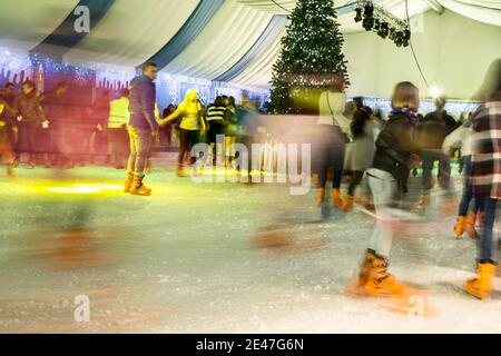 Malaga, Spanien - 08. Dezember 2017. Viele Menschen Schlittschuh auf große Eisbahn in der Winternacht, Bewegungsunschärfe Stockfoto