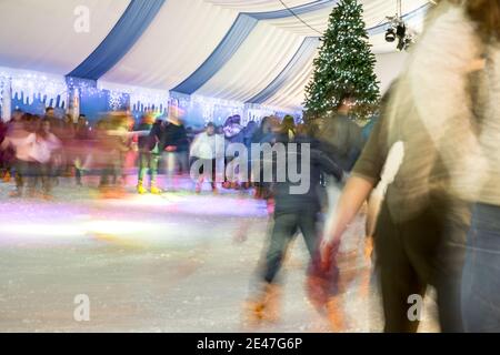 Malaga, Spanien - 08. Dezember 2017. Viele Menschen Schlittschuh auf große Eisbahn in der Winternacht, Bewegungsunschärfe Stockfoto