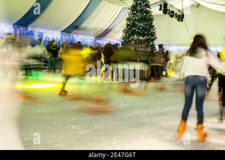 Malaga, Spanien - 08. Dezember 2017. Viele Menschen Schlittschuh auf große Eisbahn in der Winternacht, Bewegungsunschärfe Stockfoto